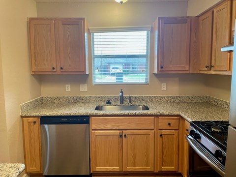 A kitchen with wooden cabinets and granite countertops.