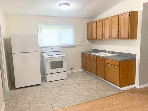 A kitchen with a white refrigerator, a white stove, and wooden cabinets.