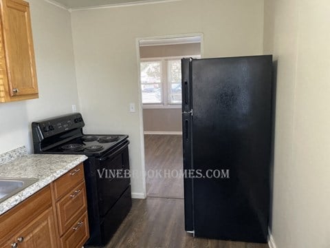 a kitchen with a black refrigerator and a stove and a window