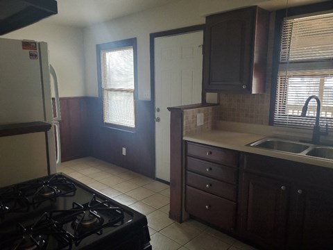A kitchen with a black stove top oven and brown cabinets.