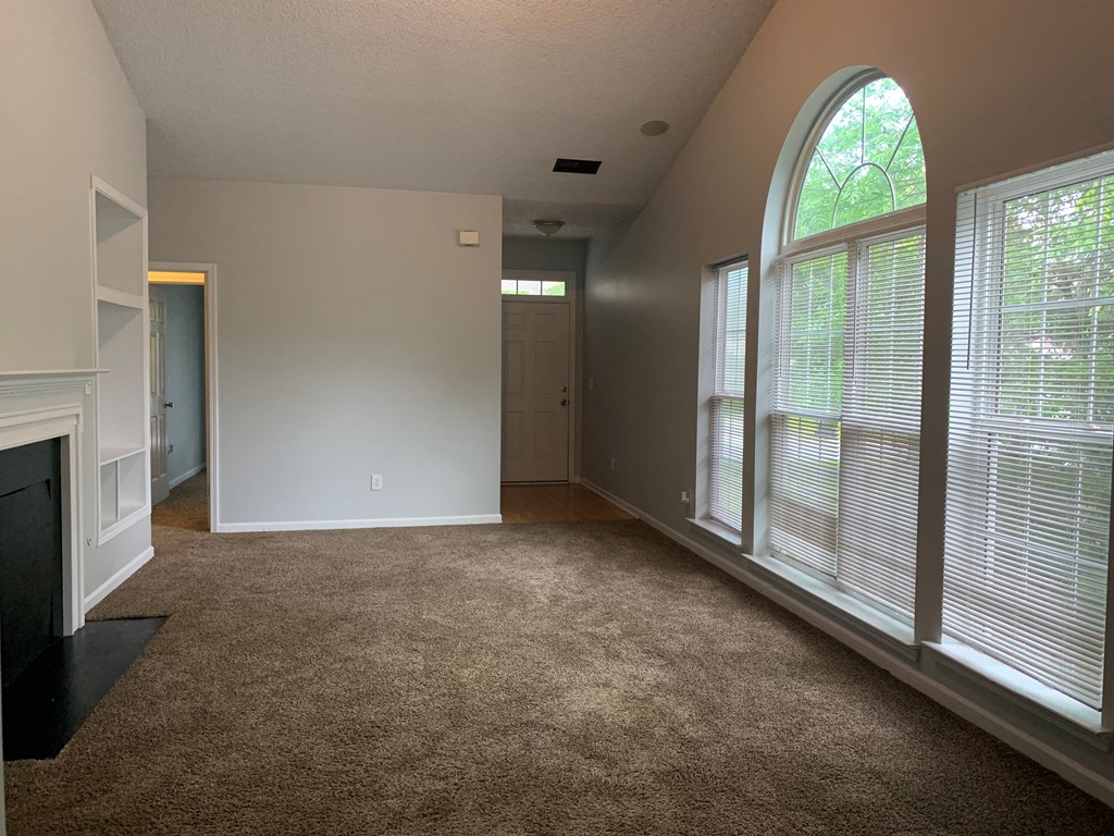 an empty living room with large windows and a fireplace