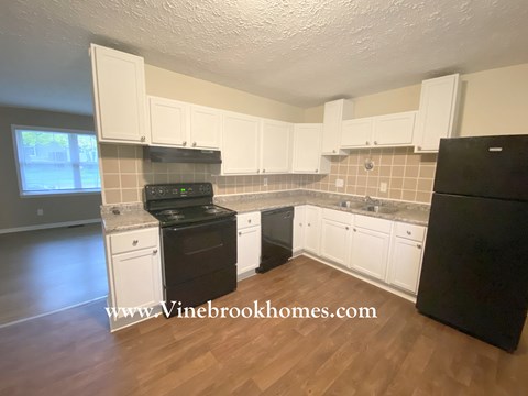 A kitchen with black appliances and white cabinets.