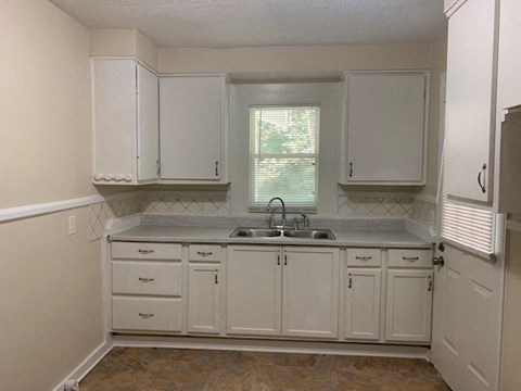 an empty kitchen with white cabinets and a sink