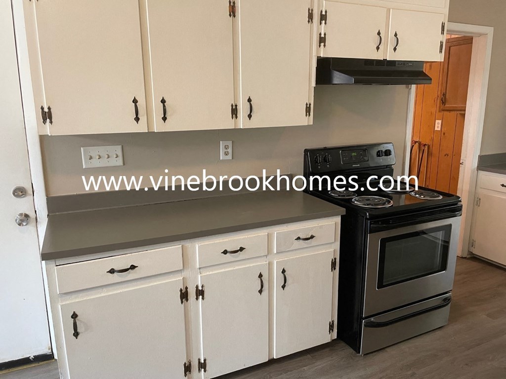 a kitchen with white cabinets and a stove and a microwave