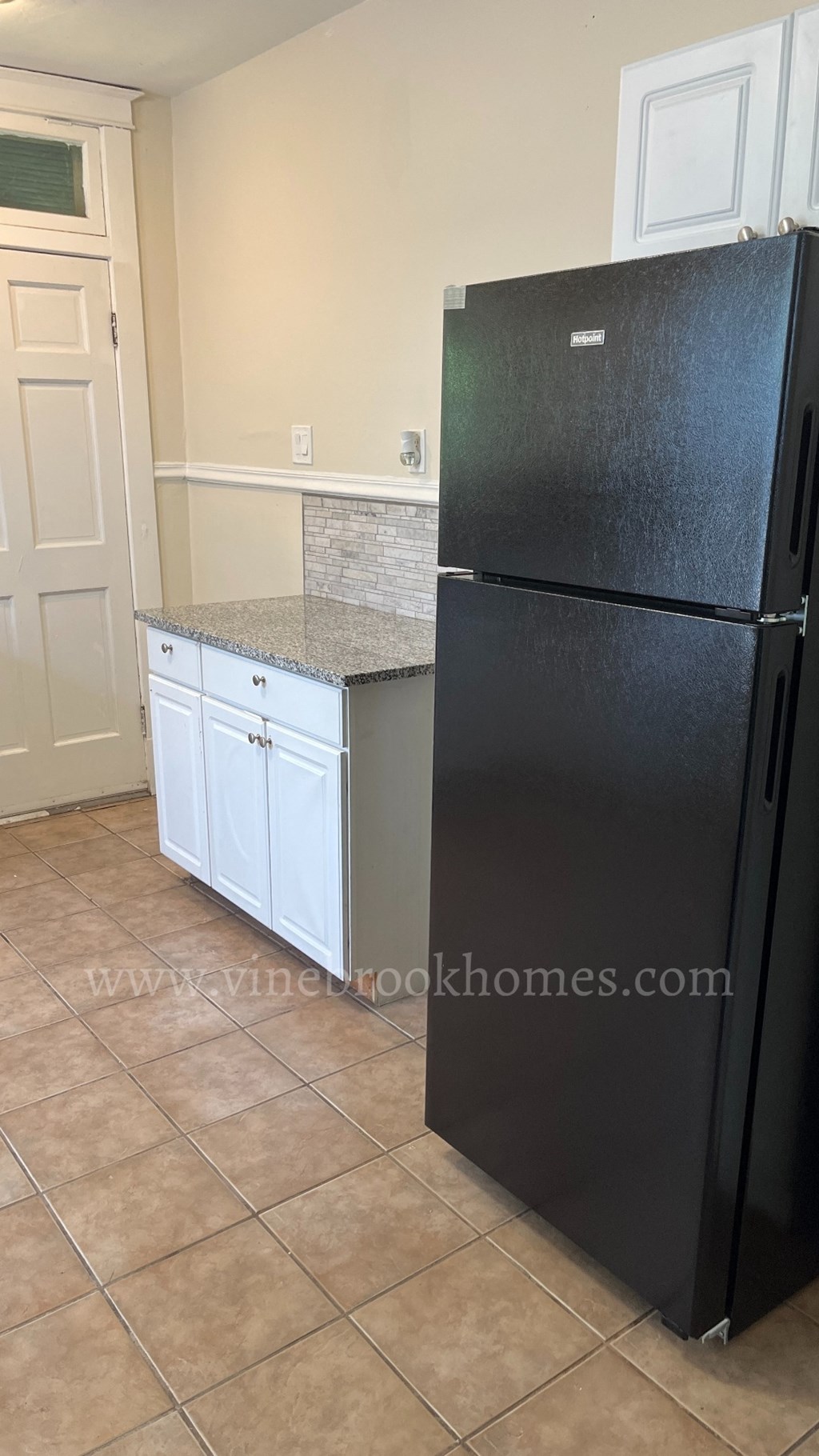 a kitchen with a black refrigerator and white cabinets