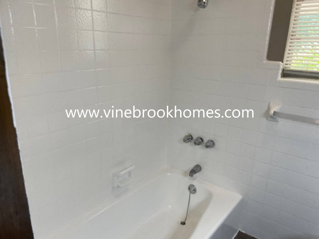 a white bath tub in a white tiled bathroom