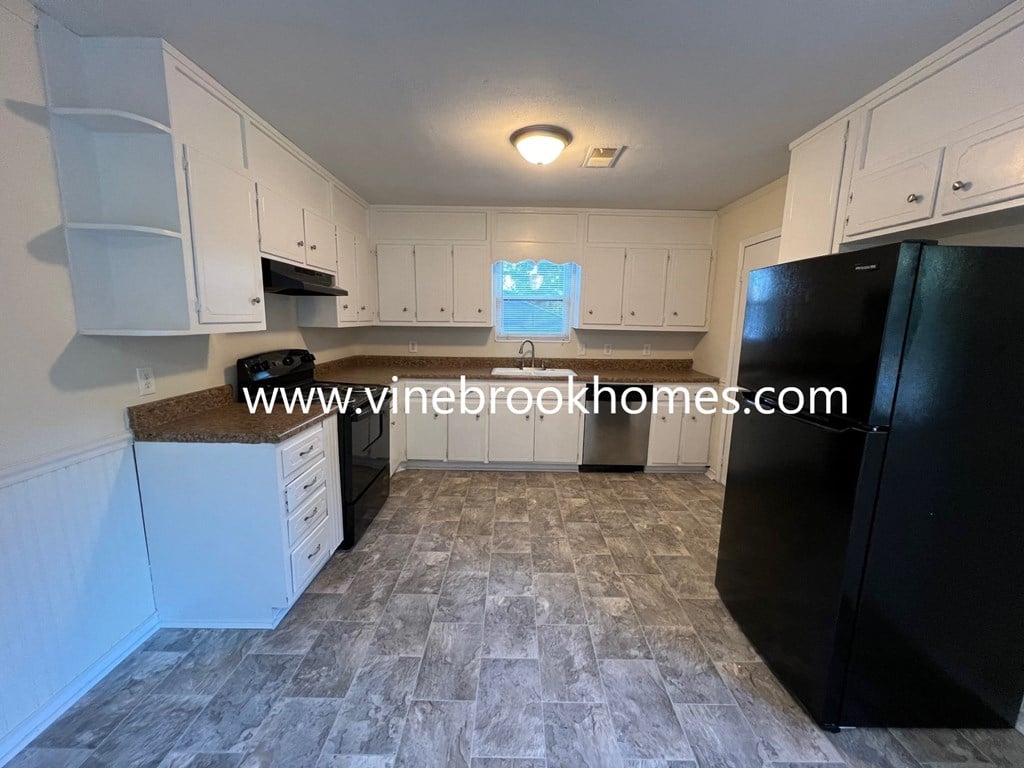 a kitchen with white cabinets and black appliances