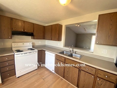 a kitchen with wooden cabinets and white appliances and a sink