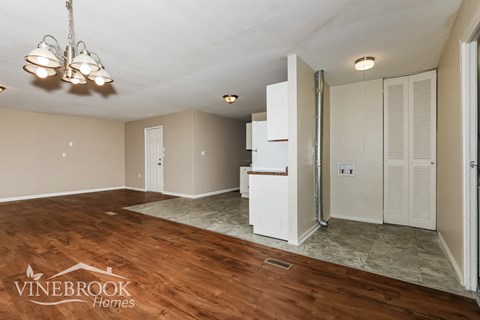 a renovated living room and kitchen with white cabinets and wood flooring