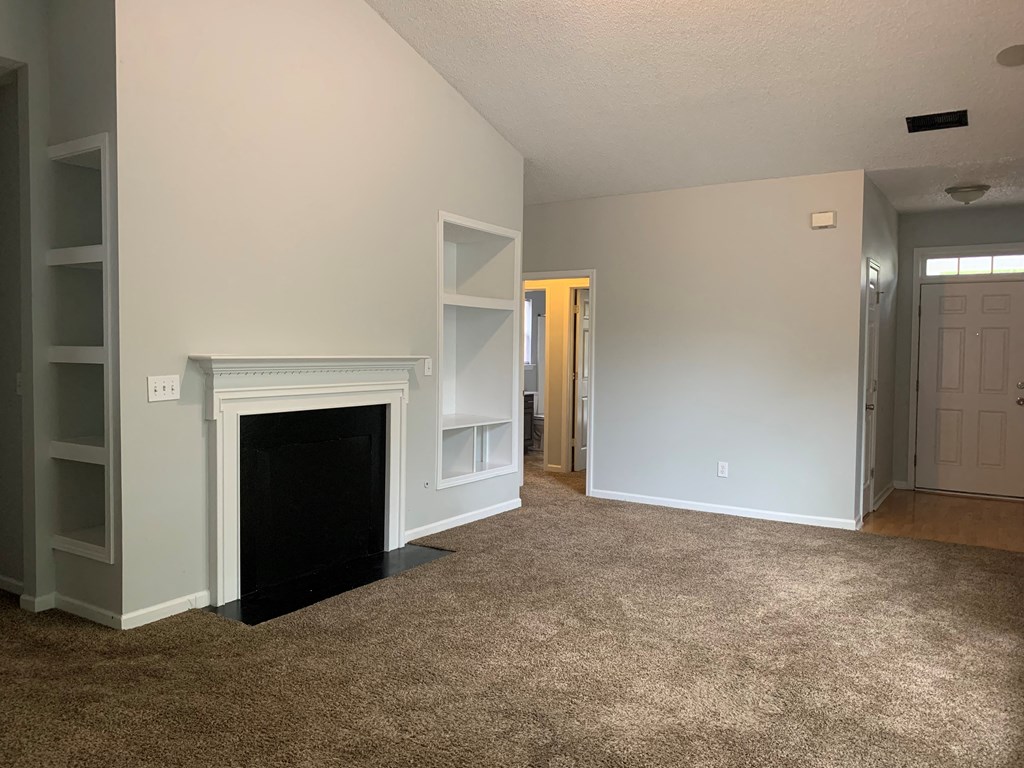 a living room with a fireplace and white shelves