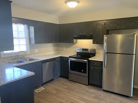 A kitchen with black cabinets and a stainless steel refrigerator.