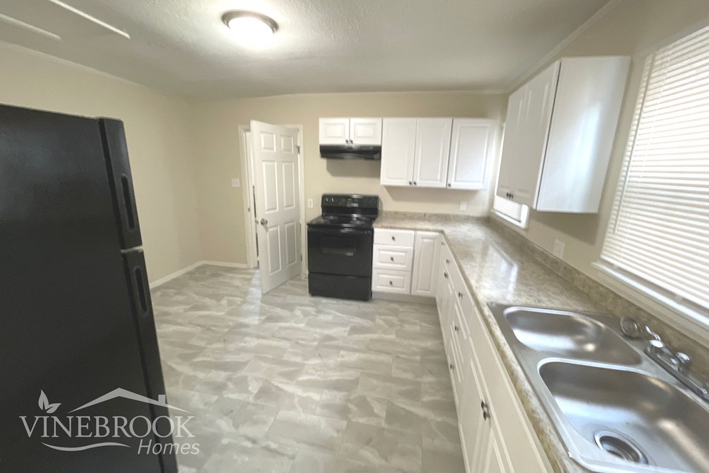 a kitchen with white cabinets and a sink and a refrigerator