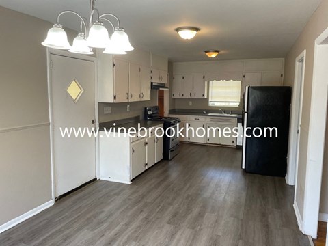 a nice sized kitchen with white cabinets and a black refrigerator