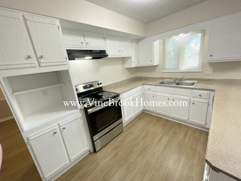 a large kitchen with white cabinets and stainless steel appliances