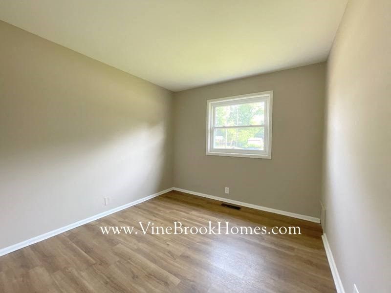 an empty room with wood floors and a window