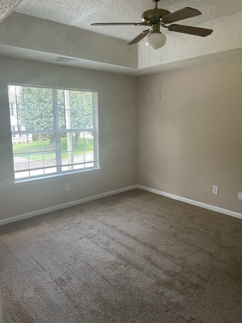 an empty living room with a ceiling fan and a window