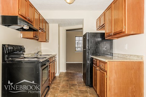 A kitchen with wooden cabinets and a black fridge.