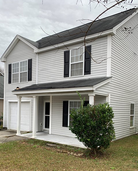 A white house with black shutters and a grey roof.