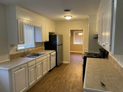 A kitchen with white cabinets and a black refrigerator.
