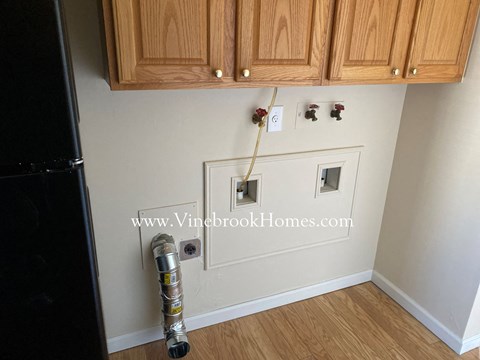 A kitchen with wooden cabinets and a black refrigerator.