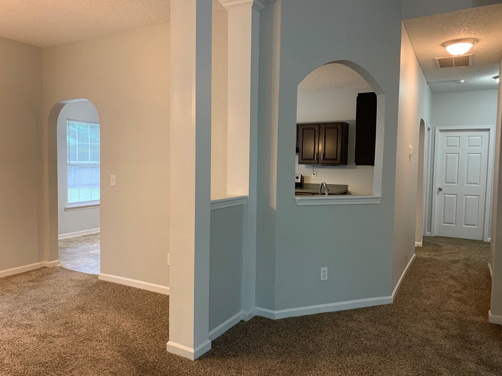 a living room with an archway and a kitchen