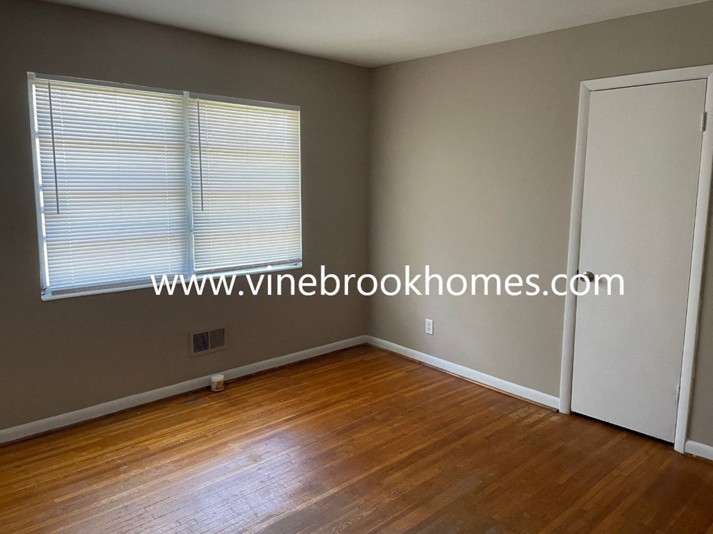 a small bedroom has a wood floor and a window