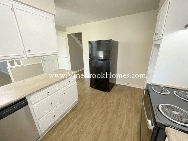 a kitchen with white cabinets and a black refrigerator