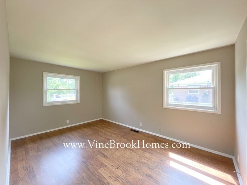 a room with a hard wood floor and two windows