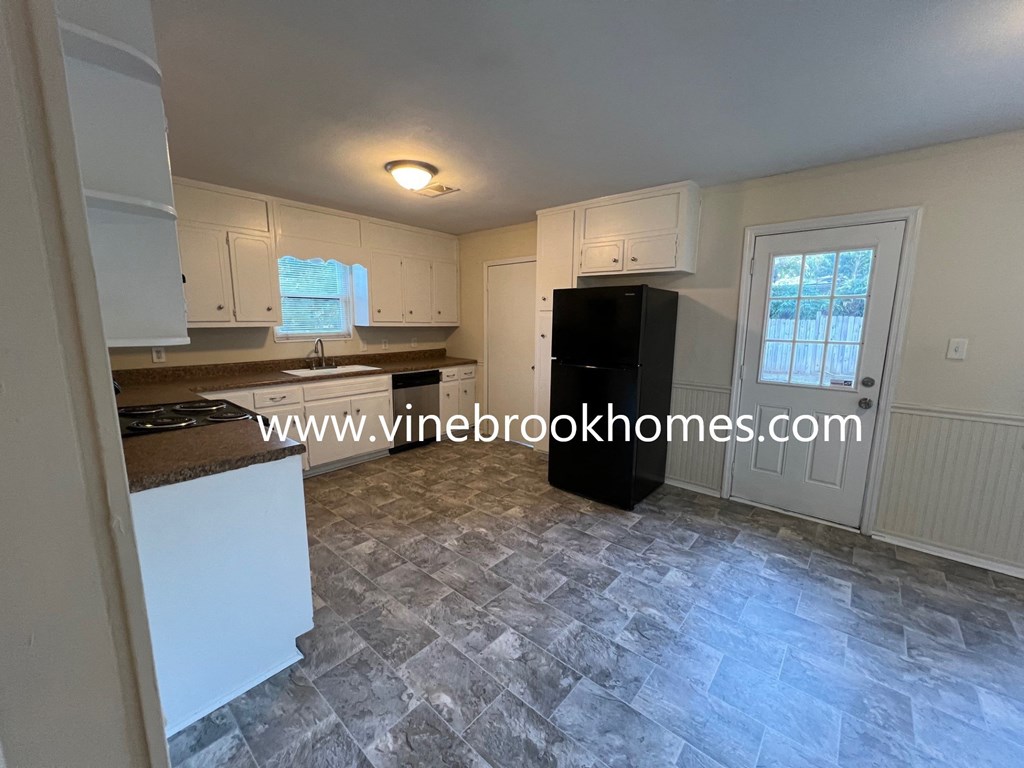 a kitchen with white cabinets and a black refrigerator