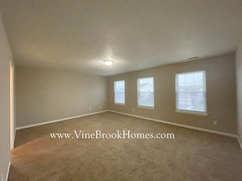 a living room with a carpet and three windows