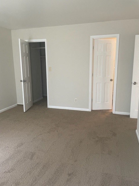 an empty room with a carpeted floor and two doors