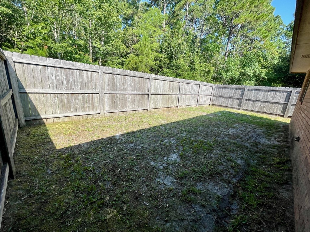 a backyard with a wooden fence and grass