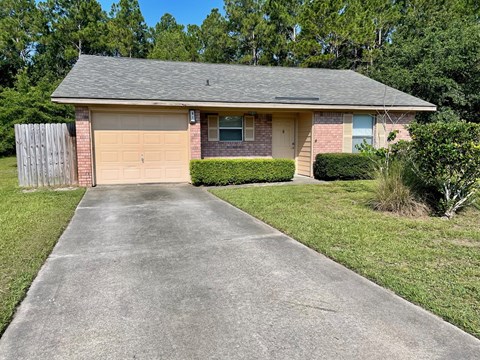 a small brick house with a driveway and a garage door