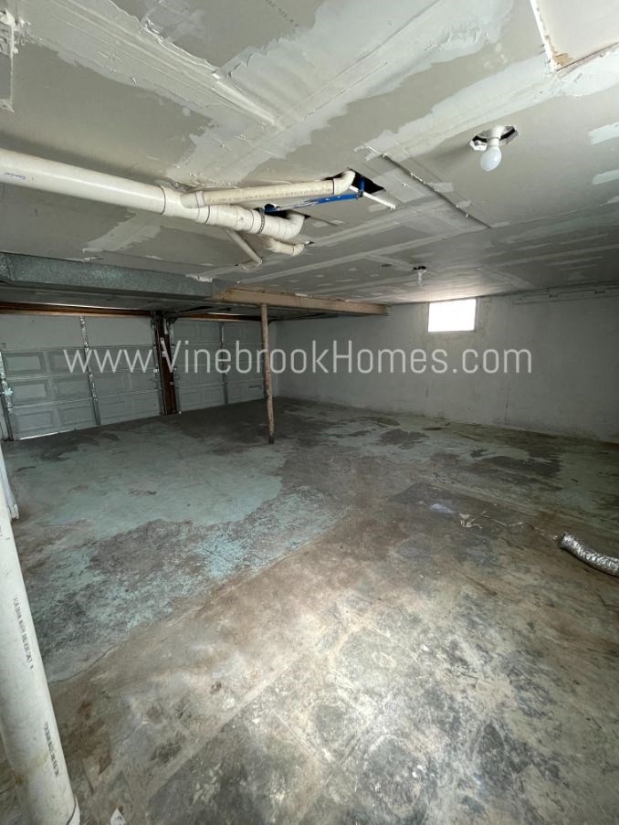 a garage with a cement floor and pipes on the ceiling
