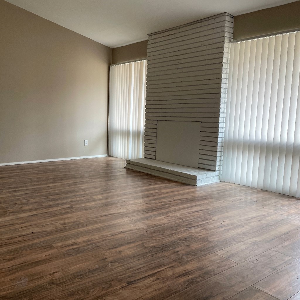 an empty living room with wood floors and a fireplace