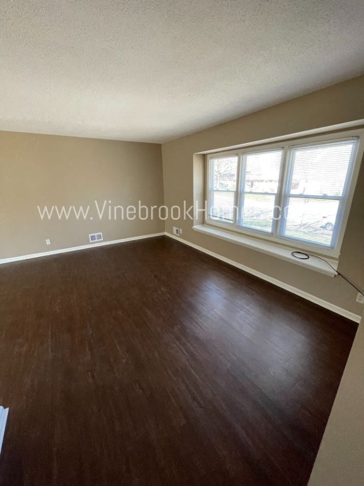 an empty living room with wood floors and a large window