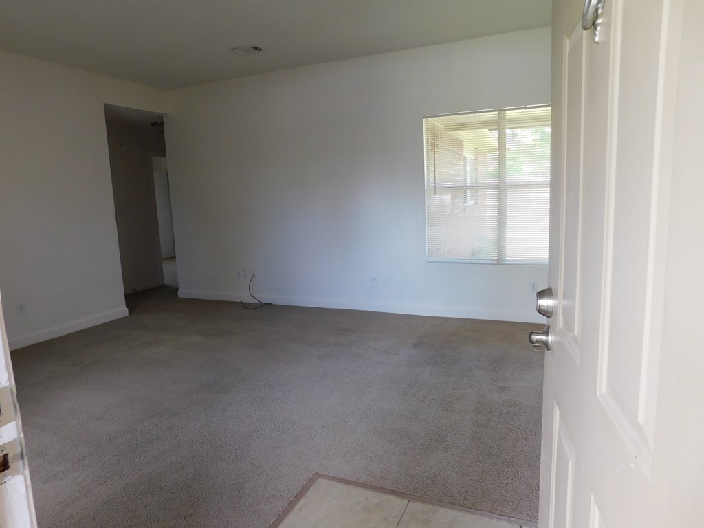 A room with a white door and a window with blinds.