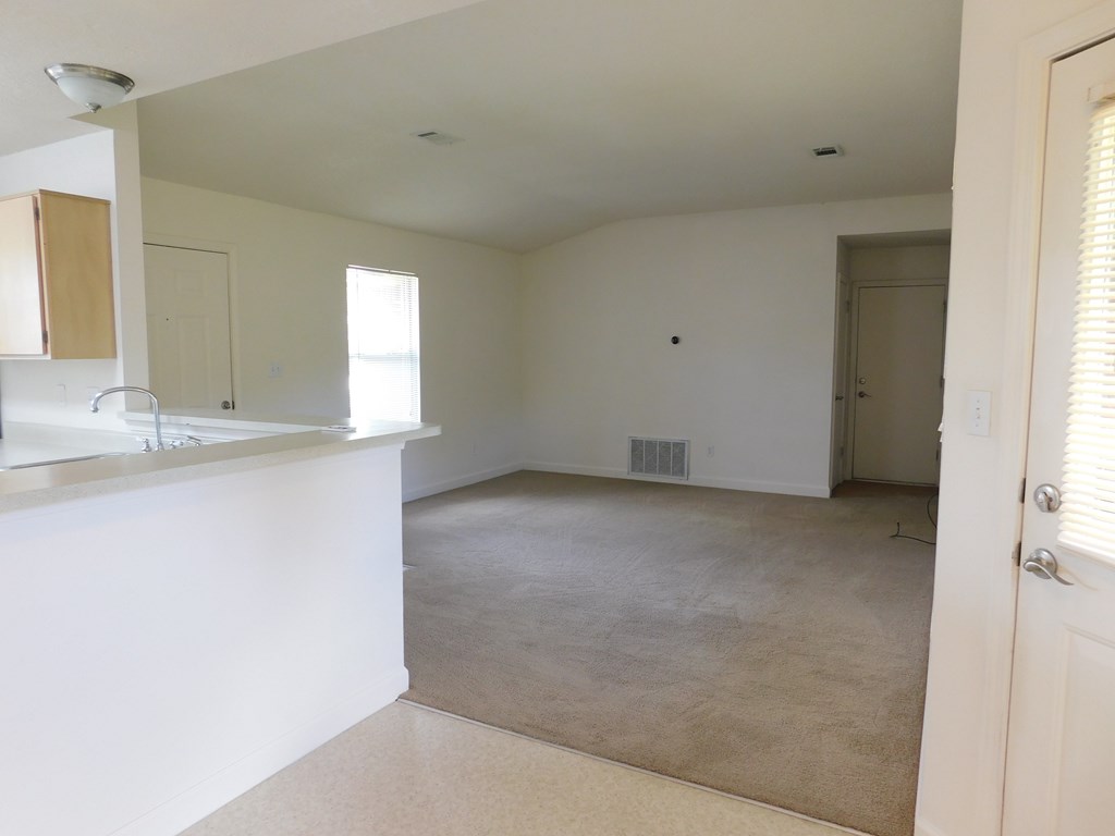 A white kitchen with a counter and a window.