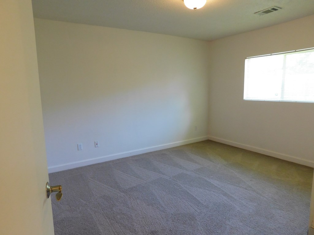 A room with a carpeted floor and a door on the left side.