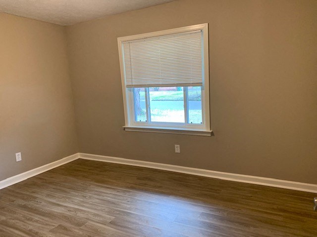 an empty room with a window and wooden floors