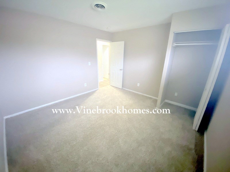 a bedroom with white walls and white carpet and a door to a closet