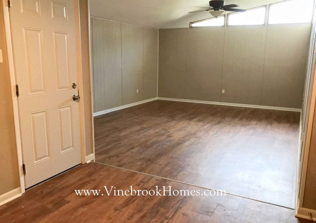 an empty living room with wood floors and a white door