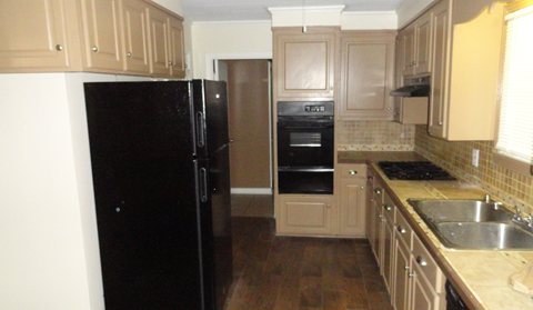 A kitchen with a black fridge and white oven.