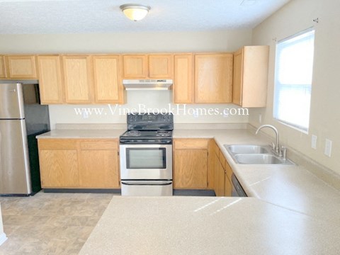 A kitchen with wooden cabinets and a stainless steel refrigerator.