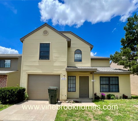 A two-story house with a garage and a driveway.