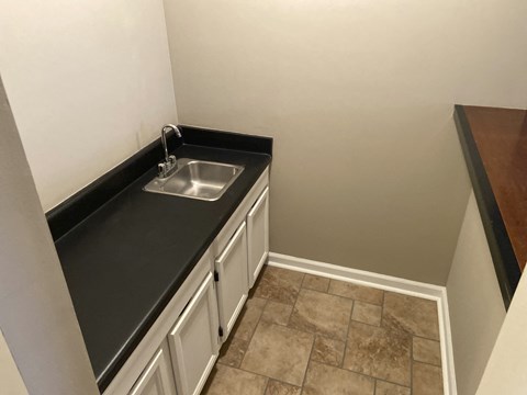 a small kitchen with a sink and white cabinets