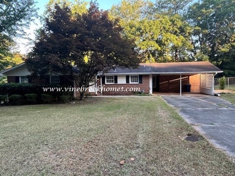 a small brick house with a yard and a tree