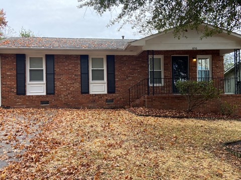 a small brick house with a yard with fallen leaves