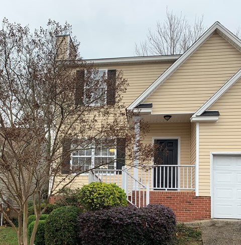 a yellow house with a porch and a white door