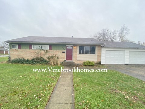 a small brick house with a red door and a lawn
